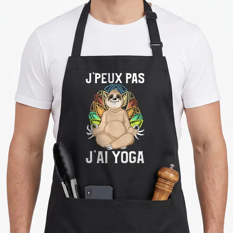 Tablier de cuisine noir avec un paresseux en position de yoga et texte blanc.