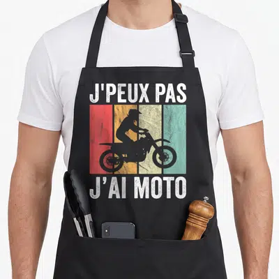 Tablier de cuisine noir avec silhouette de moto cross et texte j'peux pas j'ai moto sur fond coloré vintage.