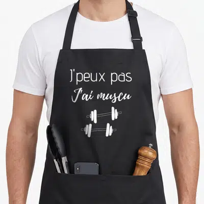 Tablier de cuisine noir avec l'inscription J'peux pas j'ai muscu et deux haltères blancs stylisés.