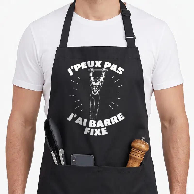 Tablier de cuisine noir avec illustration d'un homme à la barre fixe et le texte J'PEUX PAS J'AI BARRE FIXE en blanc.