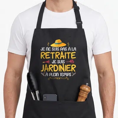 Tablier de cuisine noir avec chapeau de jardinier, tondeuse, râteau et texte jaune blanc