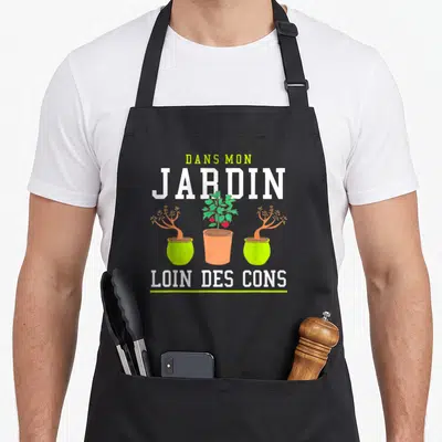 Tablier de cuisine noir avec inscription Dans mon jardin loin des cons et trois pots de fleurs colorés.