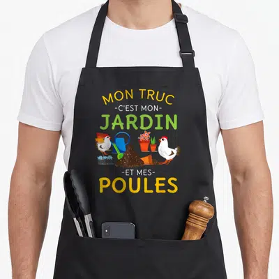 Tablier de cuisine noir avec illustration colorée de poules blanches, d'un arrosoir bleu et de pots de fleurs sur un fond de terreau.