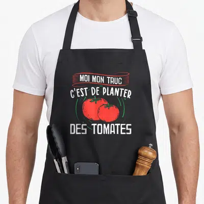 Tablier de cuisine noir avec inscription blanche et illustration de deux tomates rouges sur fond uni.