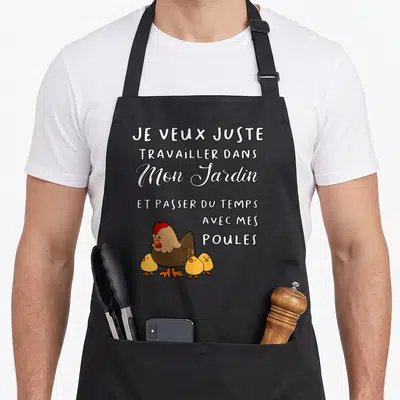 Tablier de cuisine noir avec une illustration colorée d'une poule brune et de trois poussins jaunes sous un texte blanc en plusieurs typographies.