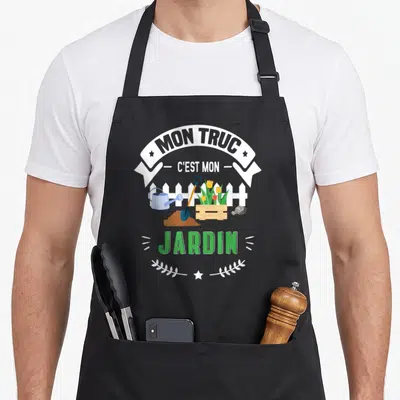 Tablier de cuisine noir avec inscription Mon Truc C'est Mon Jardin et illustration d'outils de jardinage colorés sur fond blanc.