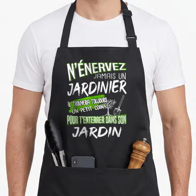 Tablier de cuisine noir avec inscription blanche et verte N'énerviez jamais un jardinier illustré d'une bêche et d'un arbre.
