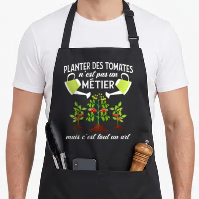 Tablier de cuisine noir avec illustration de plants de tomates et arrosoirs verts sous une citation sur le jardinage.