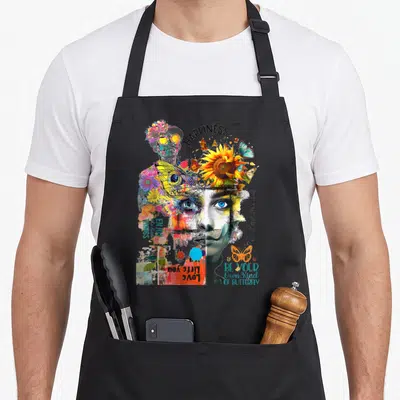 Tablier de cuisine noir avec collage artistique d'yeux bleus, papillons colorés et mots inspirants comme Happiness.