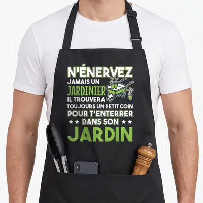 Tablier de cuisine noir avec texte vert blanc N'énervez jamais un jardinier et illustration de brouette verte à plants.