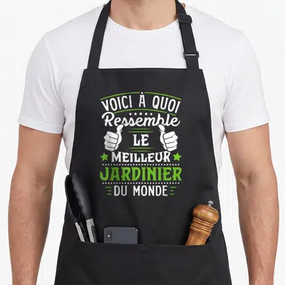 Tablier de cuisine noir avec inscription blanche et verte Voici à quoi ressemble le meilleur jardinier du monde flanqué de deux pouces levés.