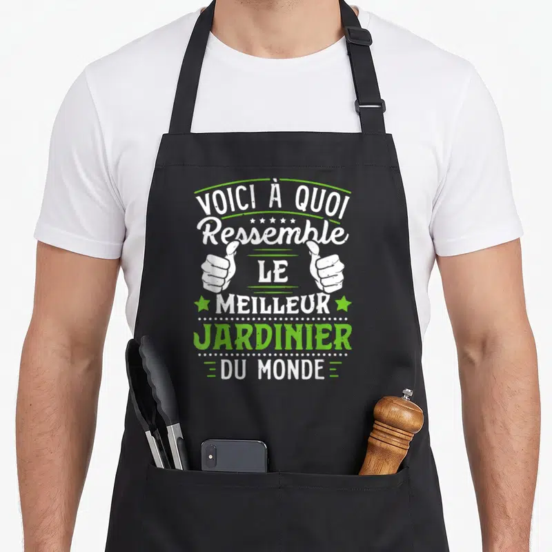 Tablier de cuisine noir avec inscription blanche et verte Voici à quoi ressemble le meilleur jardinier du monde flanqué de deux pouces levés.