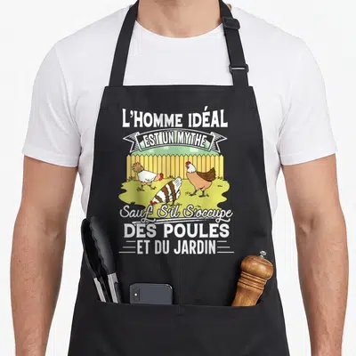 Tablier de cuisine noir avec illustration de trois poules et texte blanc sur fond de clôture jaune.