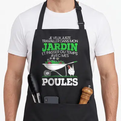 Tablier de cuisine noir avec une brouette remplie de fraises, des fleurs et une poule blanche à côté du texte imprimé en vert et blanc.