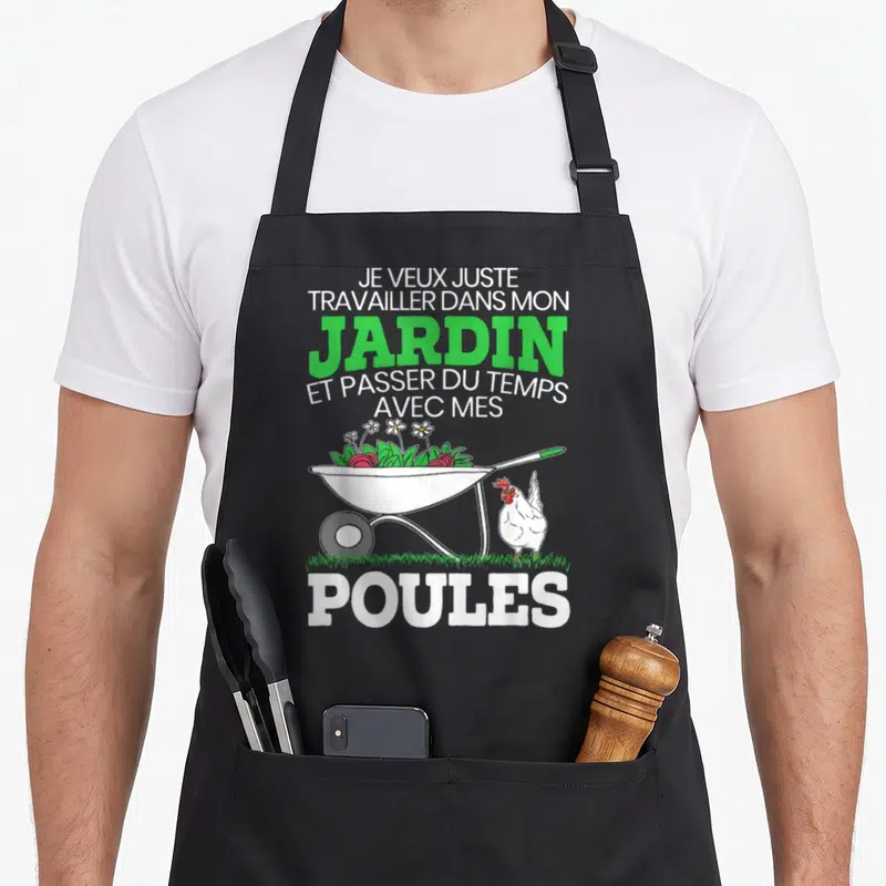 Tablier de cuisine noir avec une brouette remplie de fraises, des fleurs et une poule blanche à côté du texte imprimé en vert et blanc.