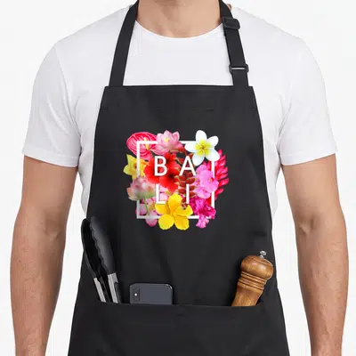 Tablier de cuisine noir avec composition florale tropicale et texte blanc BALI au centre.