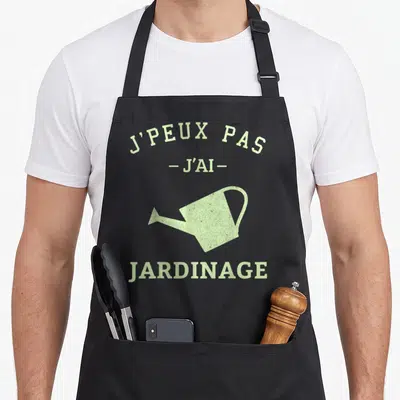 Tablier de cuisine noir avec inscription verte J'peux pas j'ai jardinage et illustration d'arrosoir vintage.