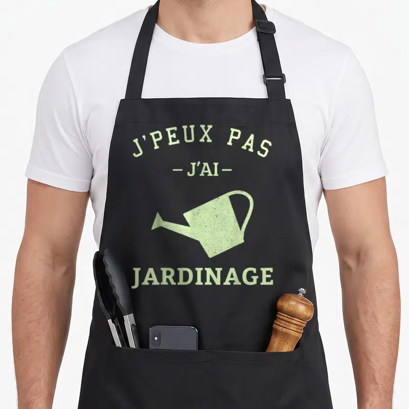 Tablier de cuisine noir avec inscription verte J'peux pas j'ai jardinage et illustration d'arrosoir vintage.
