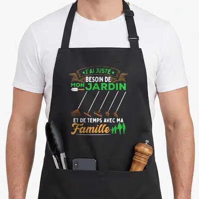 Tablier de cuisine noir avec inscription sur le jardinage et silhouettes familiales vertes ainsi que des outils de jardin orange.