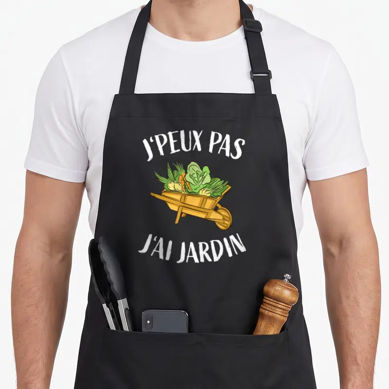 Tablier de cuisine noir avec une brouette en bois remplie de carottes et de laitues sous le texte J'peux pas j'ai jardin.