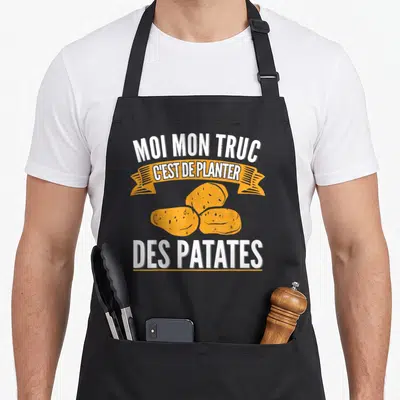 Tablier de cuisine noir avec inscription blanche et illustration de trois patates jaunes sur banderole orange.