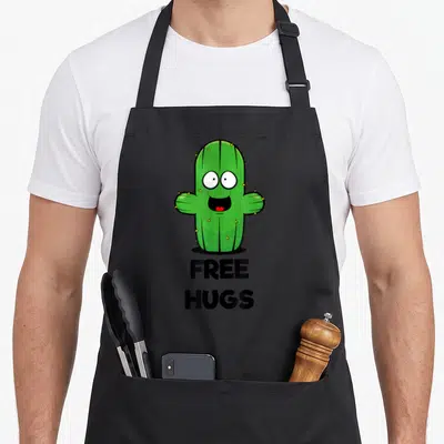Tablier de cuisine noir avec illustration cactus vert souriant et texte Free Hugs en dessous.