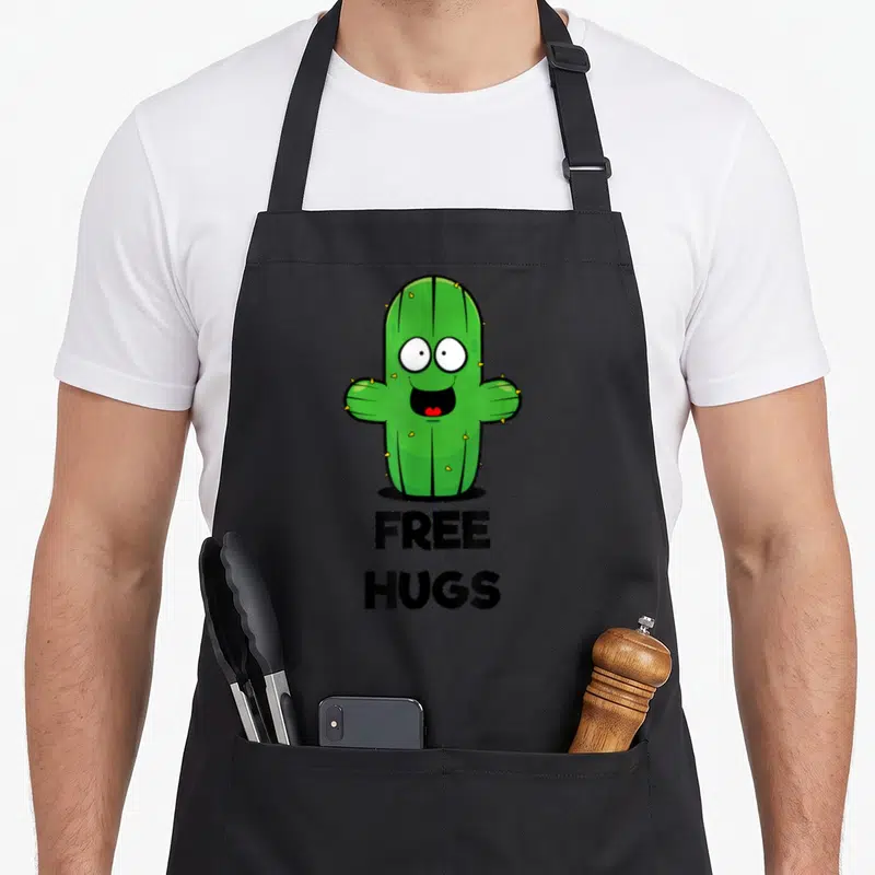 Tablier de cuisine noir avec illustration cactus vert souriant et texte Free Hugs en dessous.