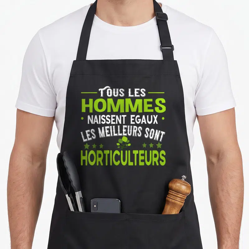 Tablier de cuisine noir avec inscription Tous les hommes naissent égaux horticulteurs et petite plante verte stylisée au centre.