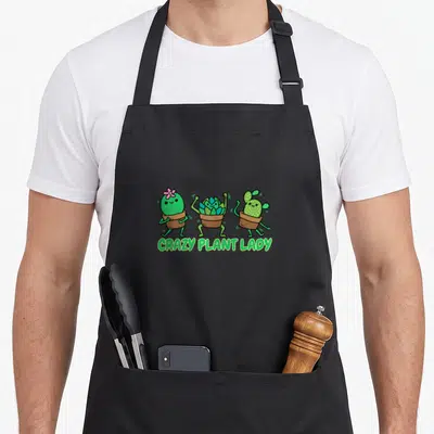 Tablier de cuisine noir avec trois cactées anthropomorphes dansant sous le texte Crazy Plant Lady en vert.