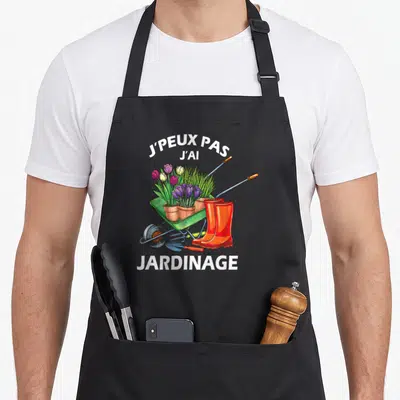 Tablier de cuisine noir avec une brouette verte remplie de tulipes et des bottes orange.