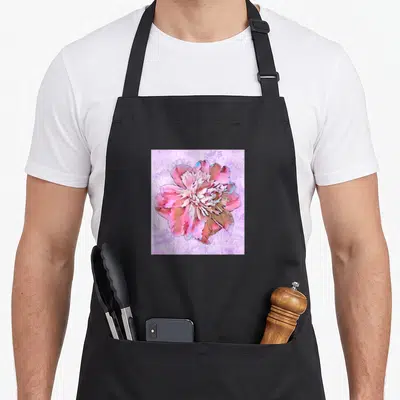 Tablier de cuisine noir avec une grande fleur rose stylisée sur fond violet texturé.