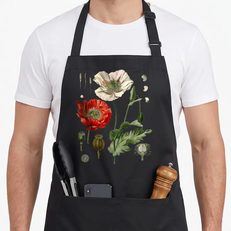 Tablier de cuisine noir avec illustration botanique de Pavot Rouge, fleurs, gousses et détails scientifiques en couleurs vives.