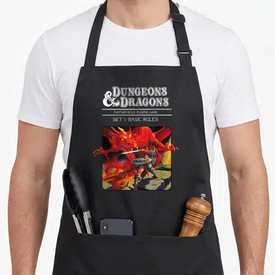 Tablier de cuisine noir avec une illustration d'un guerrier affrontant un dragon rouge sous le titre Dungeons & Dragons.