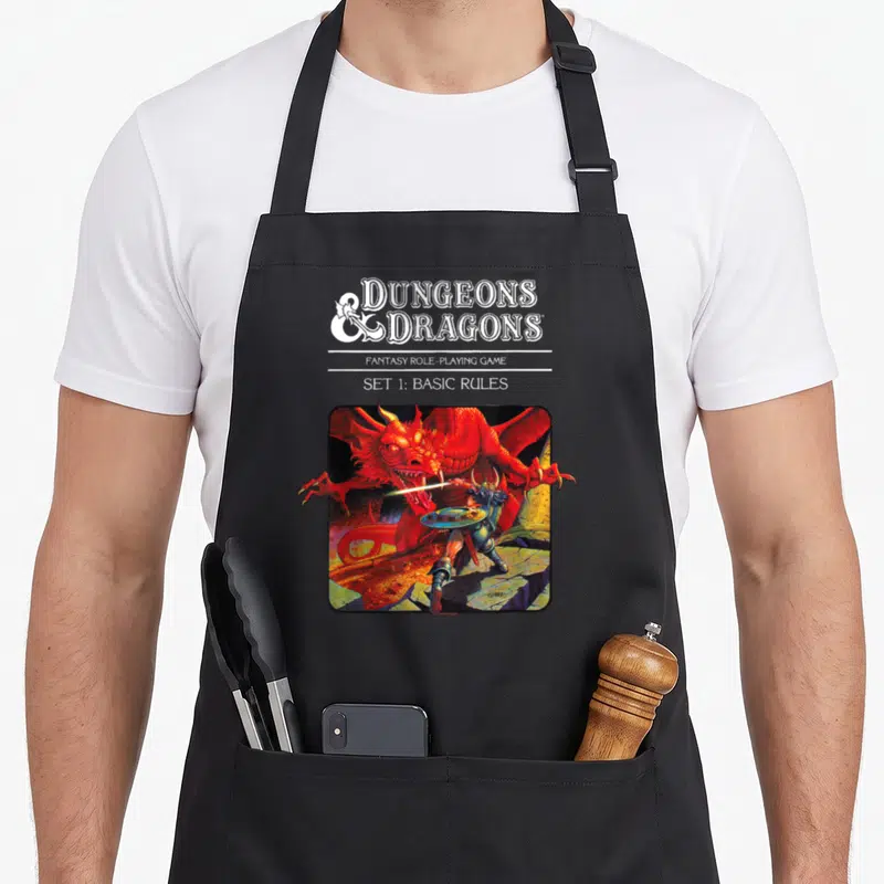 Tablier de cuisine noir avec une illustration d'un guerrier affrontant un dragon rouge sous le titre Dungeons & Dragons.