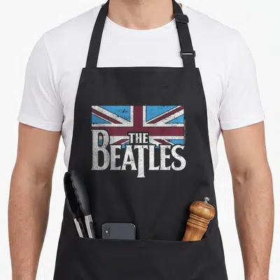 Tablier de cuisine noir avec logo The Beatles blanc et drapeau britannique bleu et rouge style vieilli.