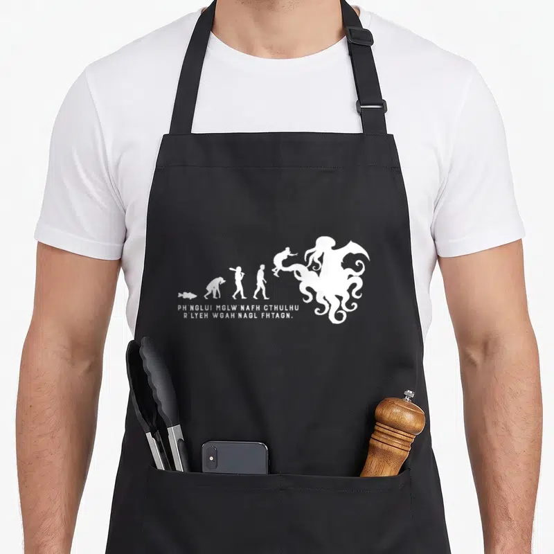 Tablier de cuisine noir avec silhouette blanche montrant l'évolution vers un monstre octopode et texte en alphabet étrange.