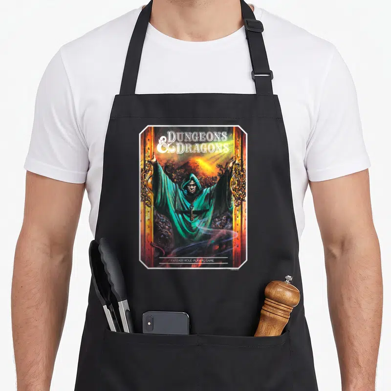 Tablier de cuisine noir avec illustration d'un magicien en capuche verte ouvrant des portes dorées sur fond de fumée et de lumière orange.