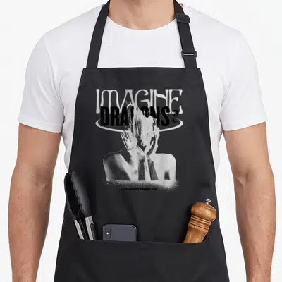 Tablier de cuisine noir avec illustration blanche Imagine Dragons et silhouette mains visage style grainé.