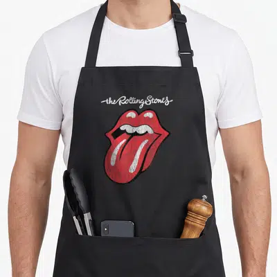 Tablier de cuisine noir avec une illustration de lèvres rouges et une langue saillante sous une écriture blanche.
