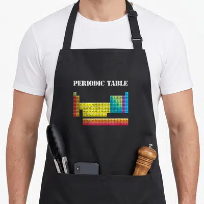 Tablier de cuisine noir avec un tableau périodique des éléments chimiques coloré et le texte periodic table en blanc vieilli.