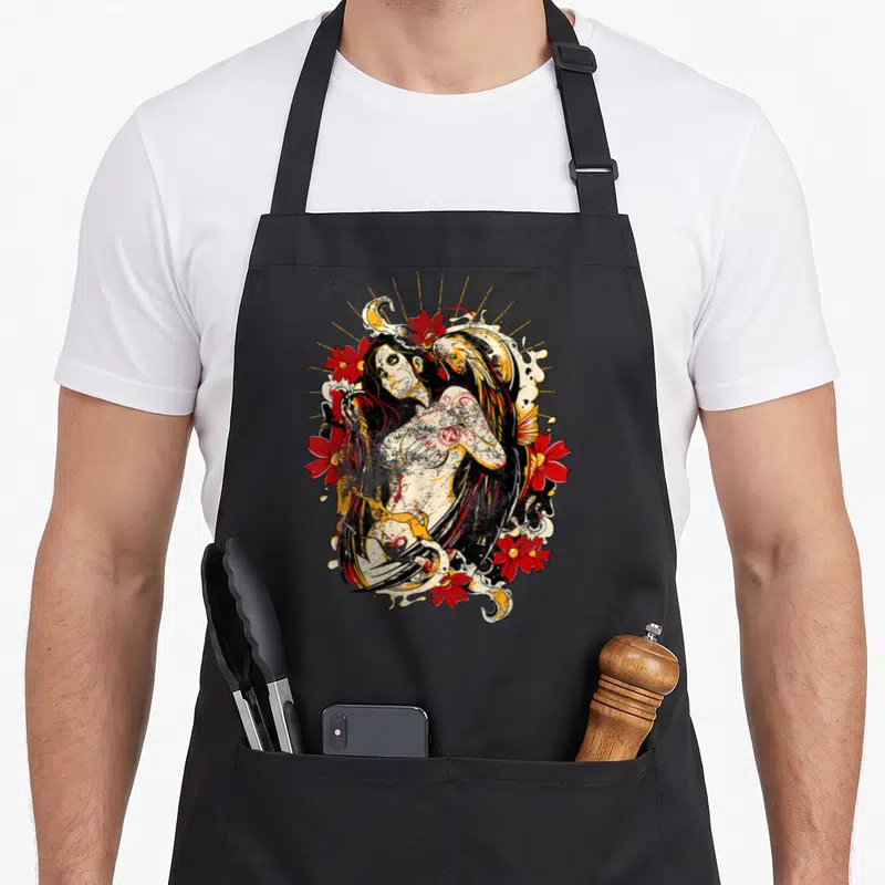 Tablier de cuisine noir avec une illustration de Catrina aux cheveux noirs, fleurs rouges et croissant doré.