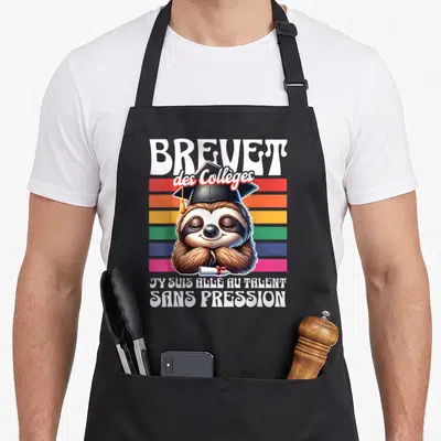 Tablier de cuisine noir avec un fourreau souriant coiffé d'une toque et tenant un diplôme sur fond de bandes colorées.