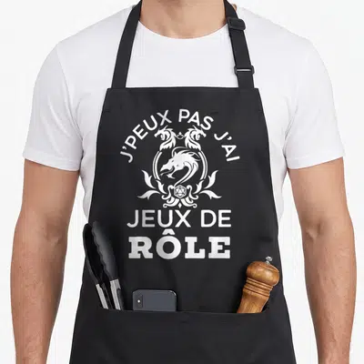 Tablier de cuisine noir avec inscription blanche J'peux pas j'ai jeux de rôle et motif de dragon stylisé.