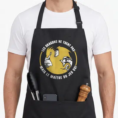 Tablier de cuisine noir avec un dragon jaune circulaire et le texte Les dragons ne tuent pas mais le maître du jeu oui.