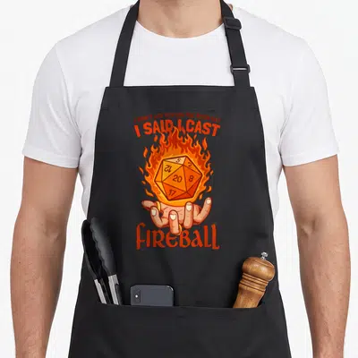 Tablier de cuisine noir avec un d20 enflammé, une main et le texte I said I cast fireball en orange.