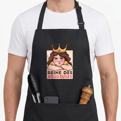 Tablier de cuisine noir avec illustration d'une reine boudeuse coiffée d'une couronne dorée et du texte REINE DES BOUDEUSES en dessous.