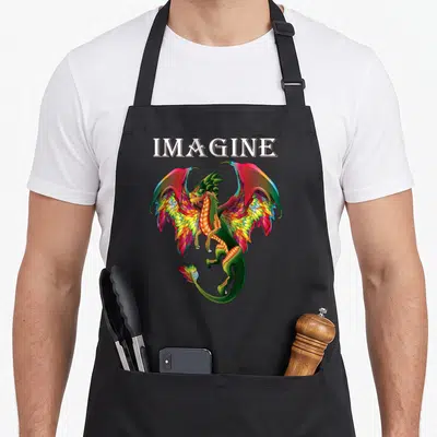 Tablier de cuisine noir avec un dragon aux ailes colorées et le mot Imagine en lettres stylisées.