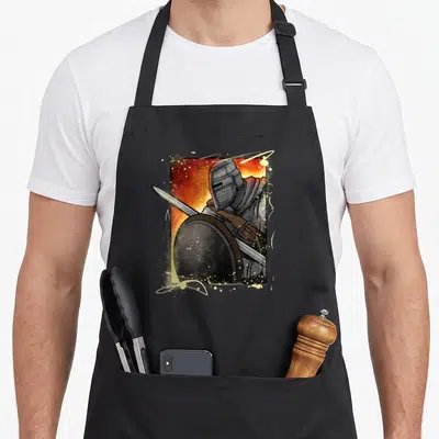 Tablier de cuisine noir avec illustration d'un chevalier casqué brandissant une épée et un bouclier rond sur fond orangé.