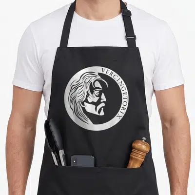 Tablier de cuisine noir avec le profil stylisé de Vercingetorix dans un cercle blanc.