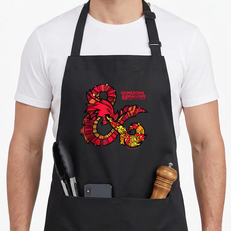 Tablier de cuisine noir avec un ampersand stylisé en mosaïque rouge et jaune représentant un dragon pour Dungeons & Dragons Honor Among Thieves.